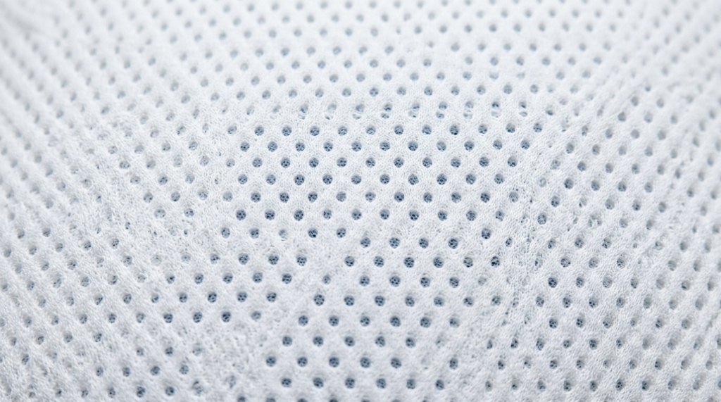Close-up of a breathable cooling memory foam pillow surface with micro-perforations.