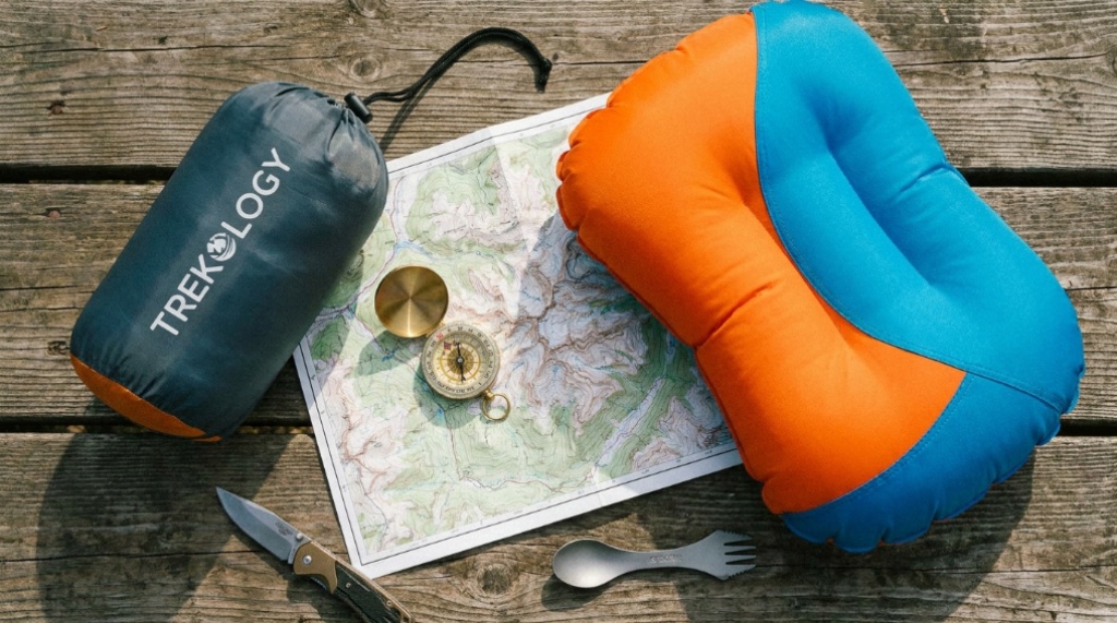 Side-by-side view of memory foam and inflatable camping pillows on wooden table.